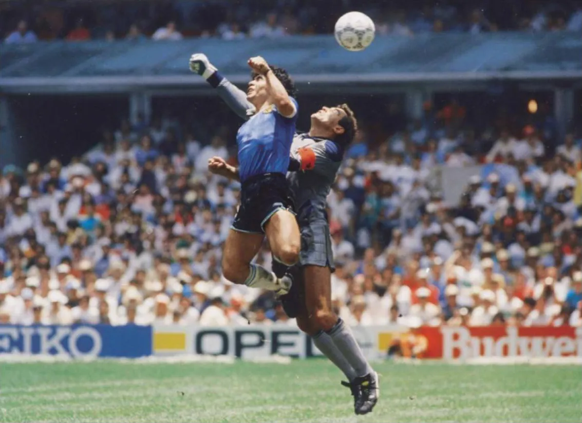 Diego Maradona saat mencetak gol dengan tangan melawan Peter Shilton di Piala Dunia 1986